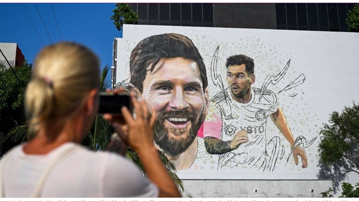 A woman takes a photo of Argentine artist Maximiliano Bagnasco's giant mural of international soccer star Lionel Messi in Wynwood, Miami’s art district, in Miami, Florida