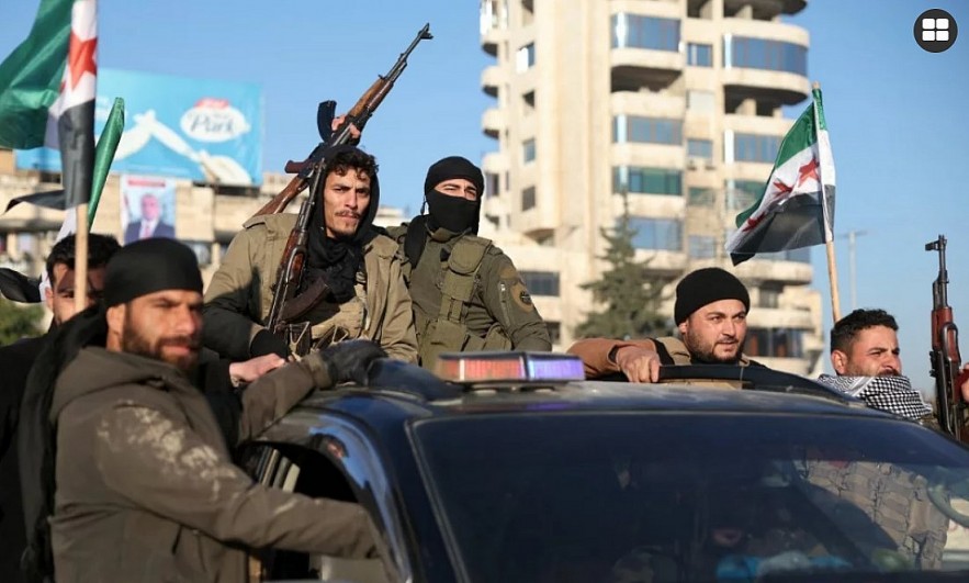 Anti-government fighters brandish their guns as they ride a vehicle in Syria's northern city of Aleppo 