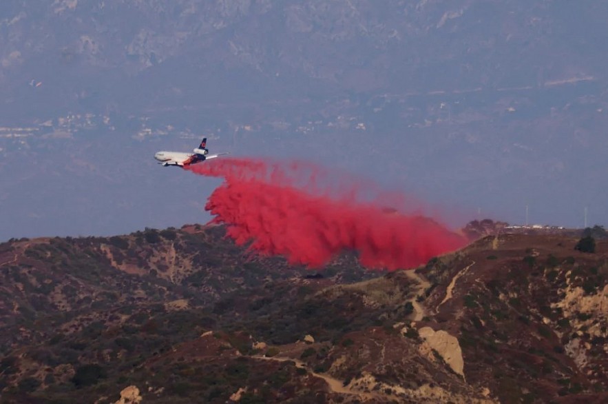 A tanker drops retardant as the Palisades Fire grows in the mountains in Topanga, Calif