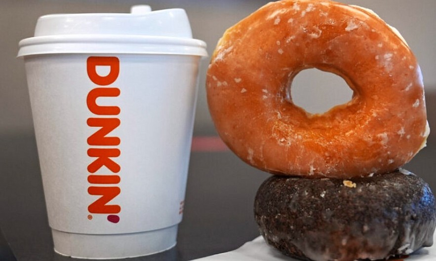 Two donuts and a cup of coffee rest on a counter at a Dunkin' location