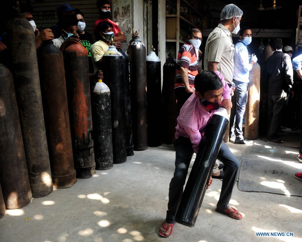 A man lifts a refilled medical oxygen cylinder for COVID-19 patients in front of a shop in New Delhi, India, April 26, 2021. (Xinhua