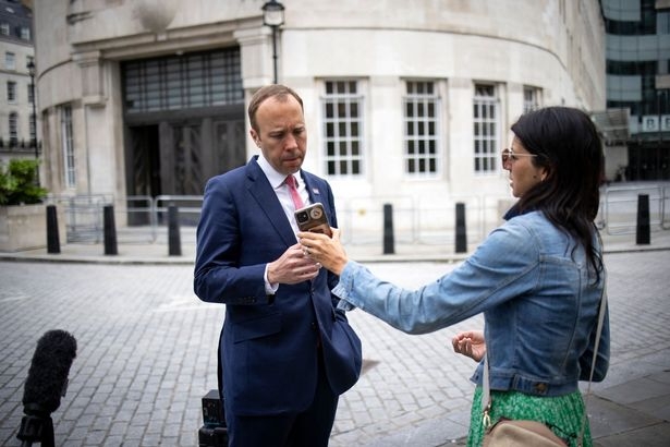Hancock looks at Mrs Coladangelo's phone as they leave the BBC on June 6. Photo Getty