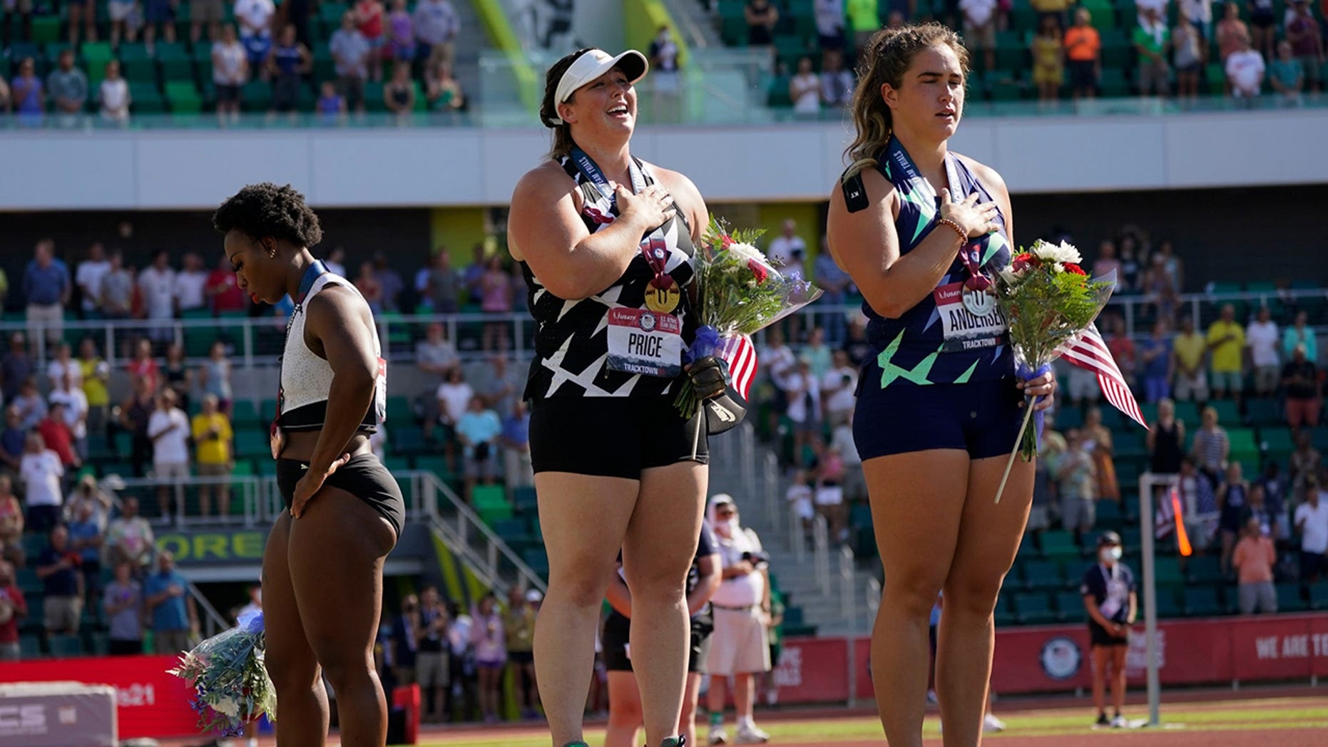 Gwendolyn Berry, left, looks away as DeAnna Price and Brooke Andersen stand for the national anthem after the finals of the women's hammer throw at the U.S. Olympic Track and Field Trials Saturday, June 26, 2021, in Eugene, Ore. Price won, Andersen was se