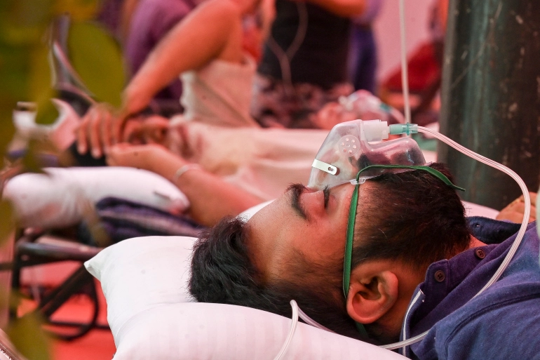 A coronavirus patient breathes with the help of oxygen provided by a Sikh temple, under a tent along the roadside in Ghaziabad [Prakash Singh/AFP]